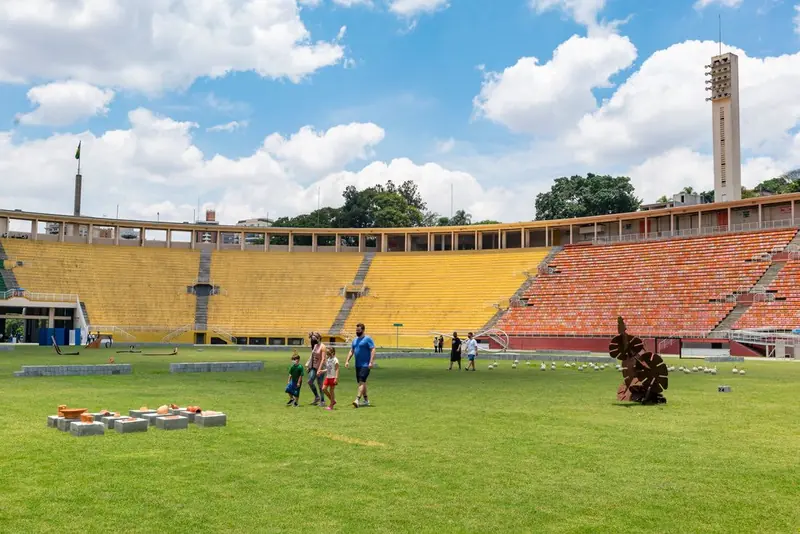 O Pacaembu hoje: pessoas caminhando no gramado aberto ao público, com as arquibancadas coloridas ao fundo